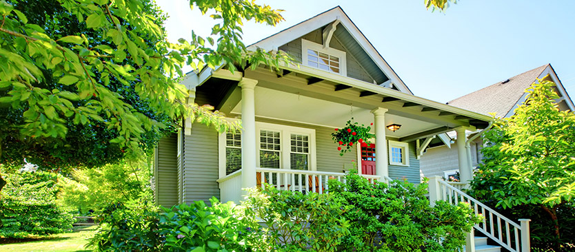 picture of white house with large porch surrounded by many trees