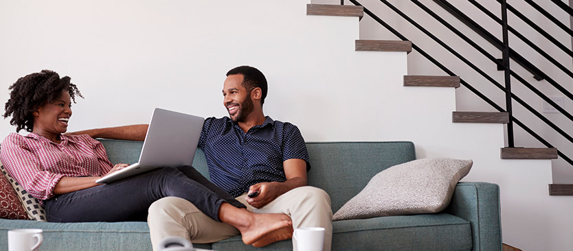 couple sitting on couch smiling and looking at each other